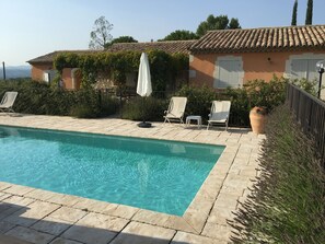 A swimming pool with clear water, surrounded by lounge chairs and a stone wall. - Country cottage with swimming pool, for 8 people, fully equipped (Pont-Saint-Esprit)