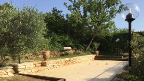 Ein Garten mit gepflastertem Weg, Steinmauern und Kübelpflanzen.