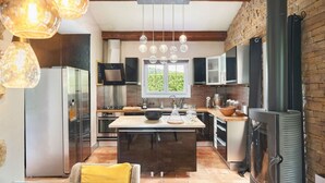 Una cocina moderna con una isla central, electrodomésticos de acero inoxidable y luces colgantes.