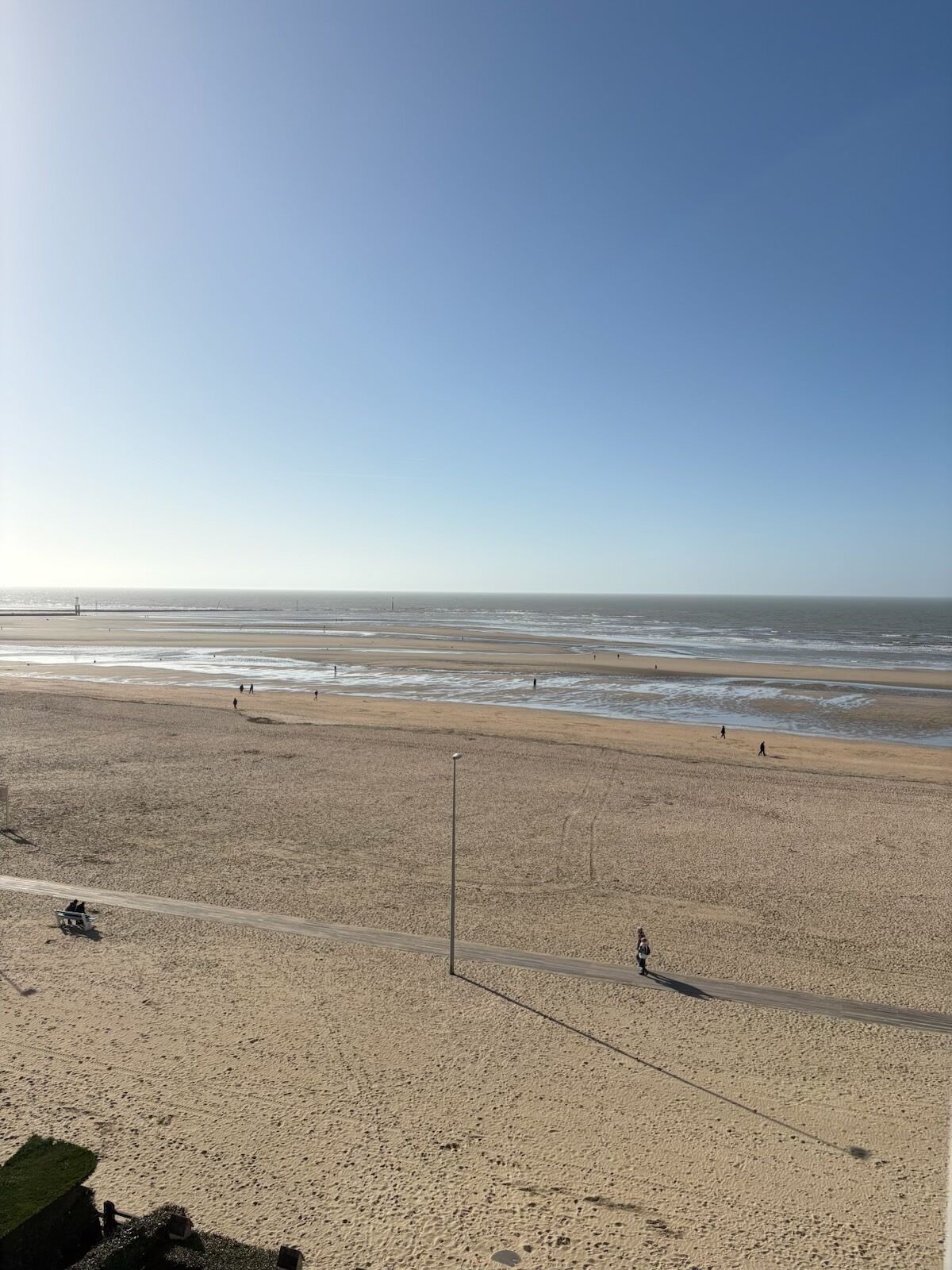 Une vaste plage de sable fin, avec un ciel dégagé et une mer calme.