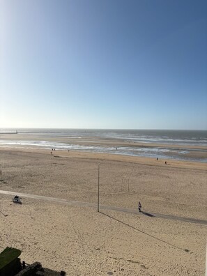 Een breed zandstrand met een heldere lucht en rustige zee.