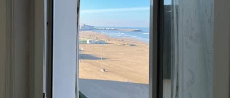 A window with a clear view of a beach and ocean.