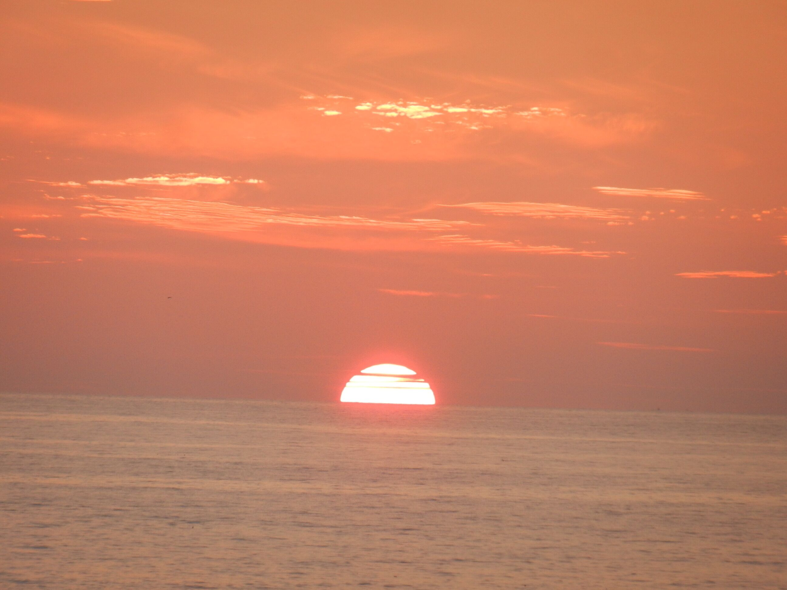 Un atardecer sobre un mar tranquilo con un horizonte despejado.