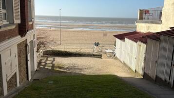 Une vue depuis un balcon donnant sur une plage, avec un ciel dégagé.