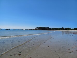 A beach with boats in the water and a sandy shore.