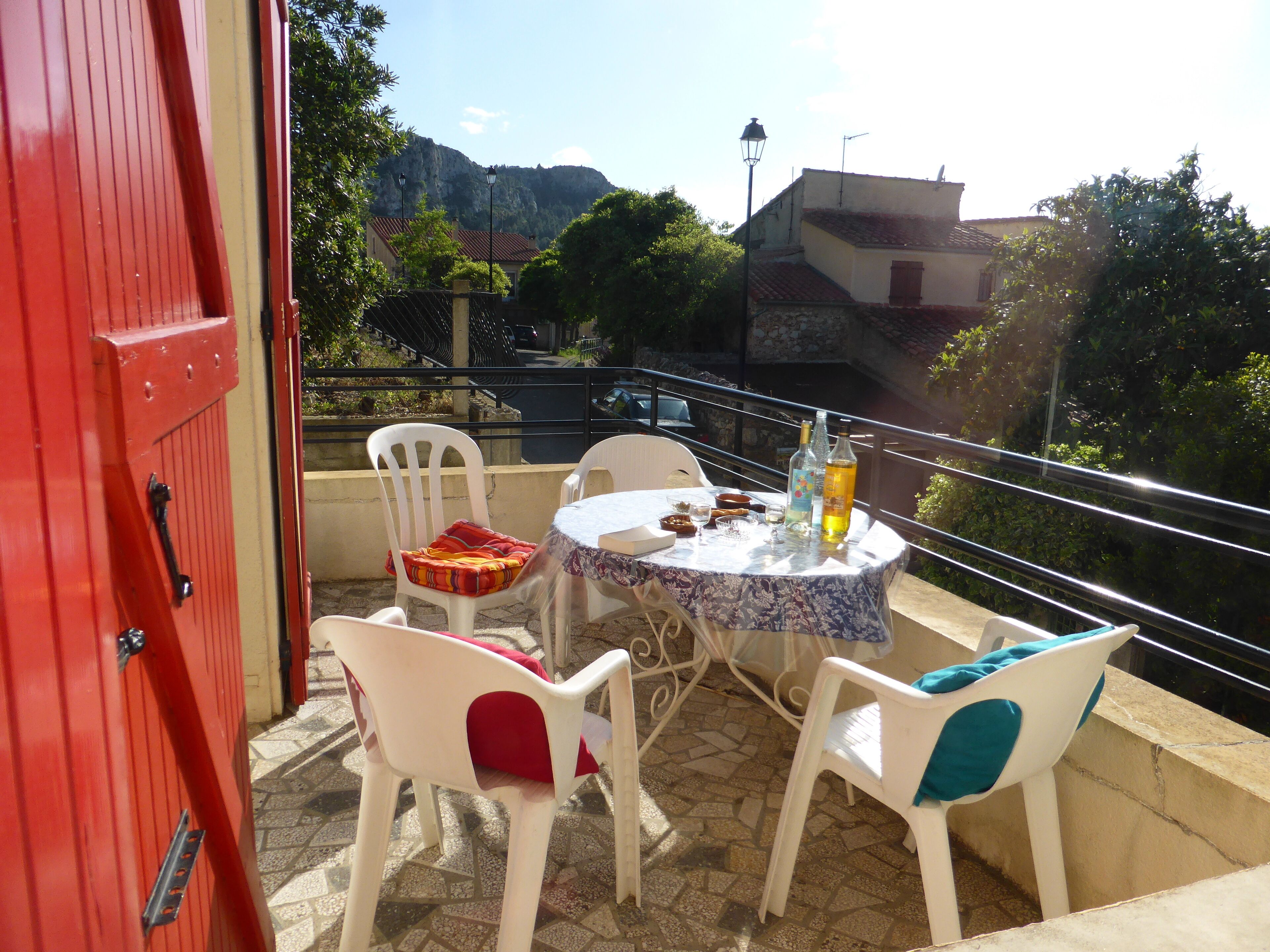 A balcony with a table, chairs, and bottles.