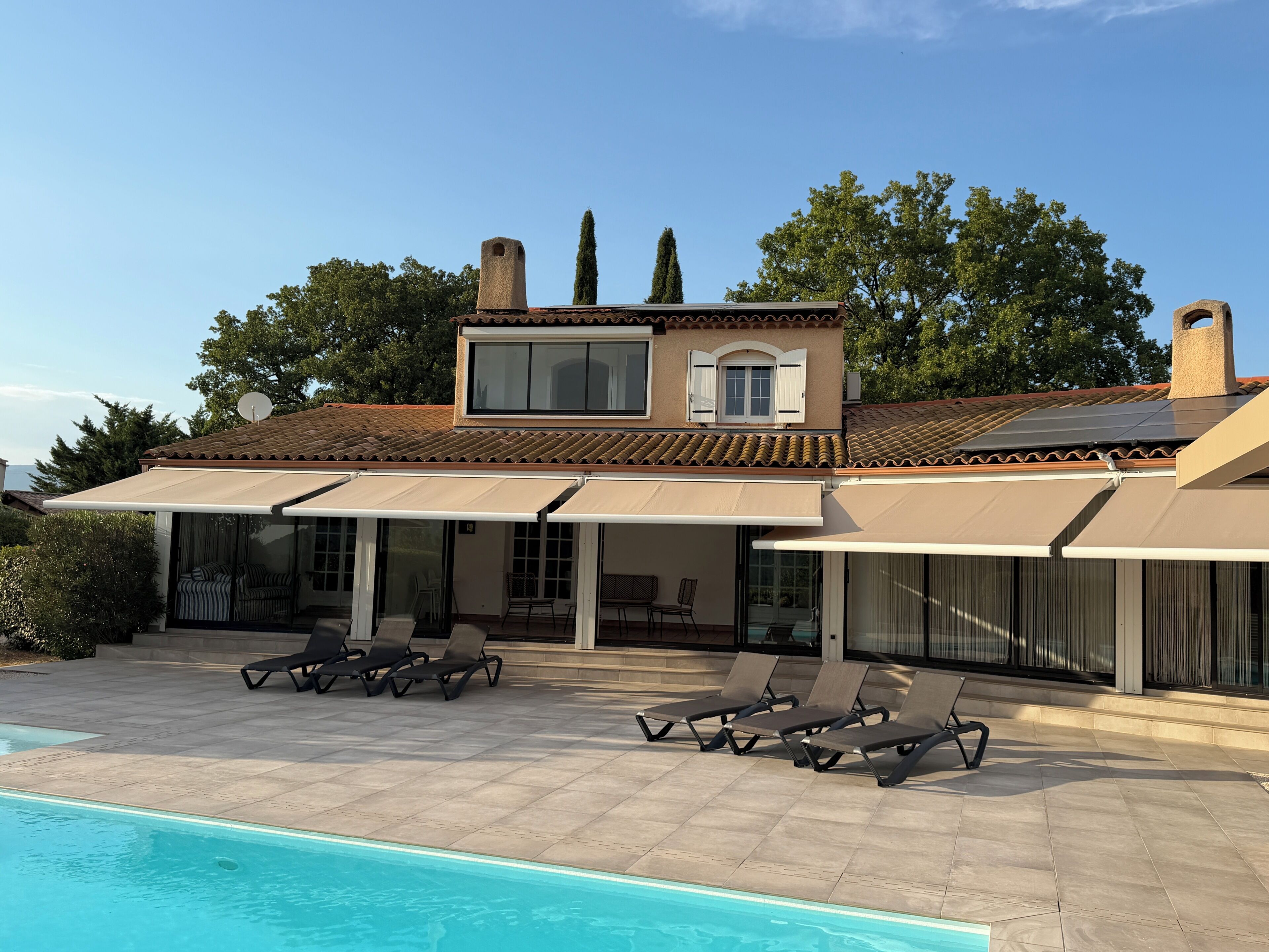 A two-story house with a swimming pool, outdoor seating, and a satellite dish.