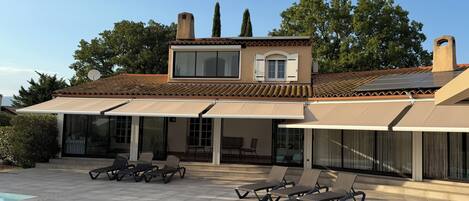 A two-story house with a swimming pool, outdoor seating, and a satellite dish.