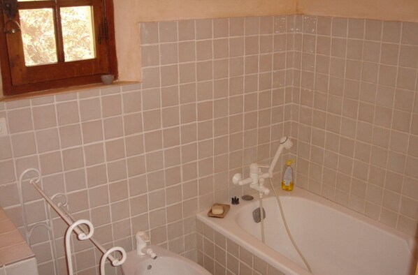 A bathroom with a bathtub, a window, and a towel rack.
