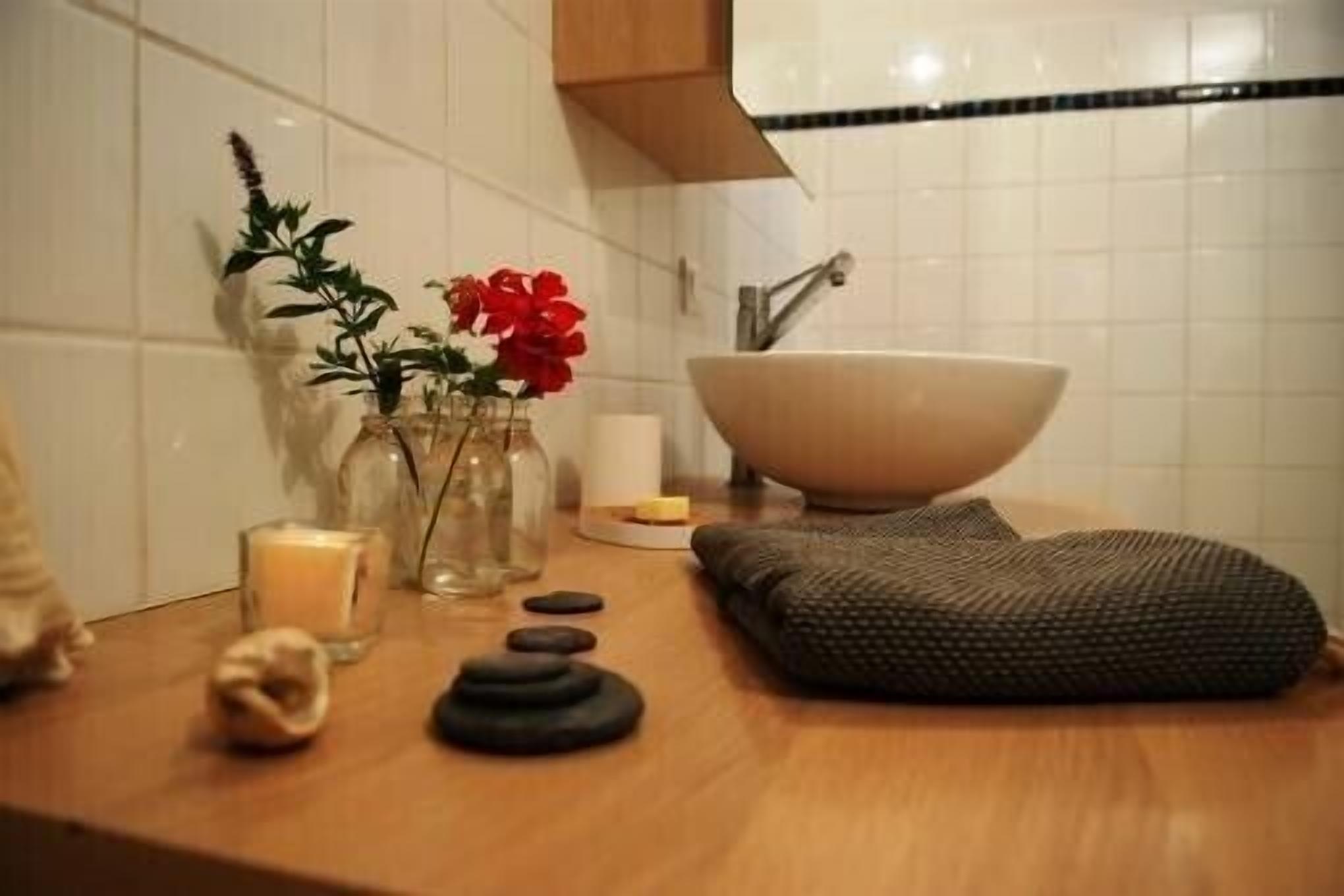 Un baño con un lavamanos grande, una toalla, una vela y una planta pequeña en la encimera.
