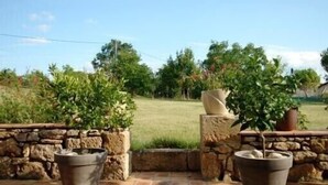A patio area with stone walls and potted plants. - Adorable guest apartment at the pool (Prayssas)