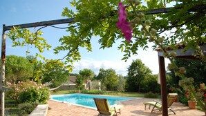 A backyard with a swimming pool, two lounge chairs, and a pergola with climbing plants. - Adorable guest apartment at the pool (Prayssas)