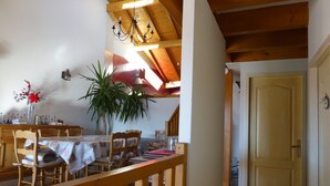 A dining area with wooden furniture, a chandelier, and a potted plant. - Beautiful duplex of 110 m² in a chalet style Full of charm, awarded 3 stars (Théus)