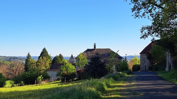 Landskab med et stenhus, en kirke og en vej.