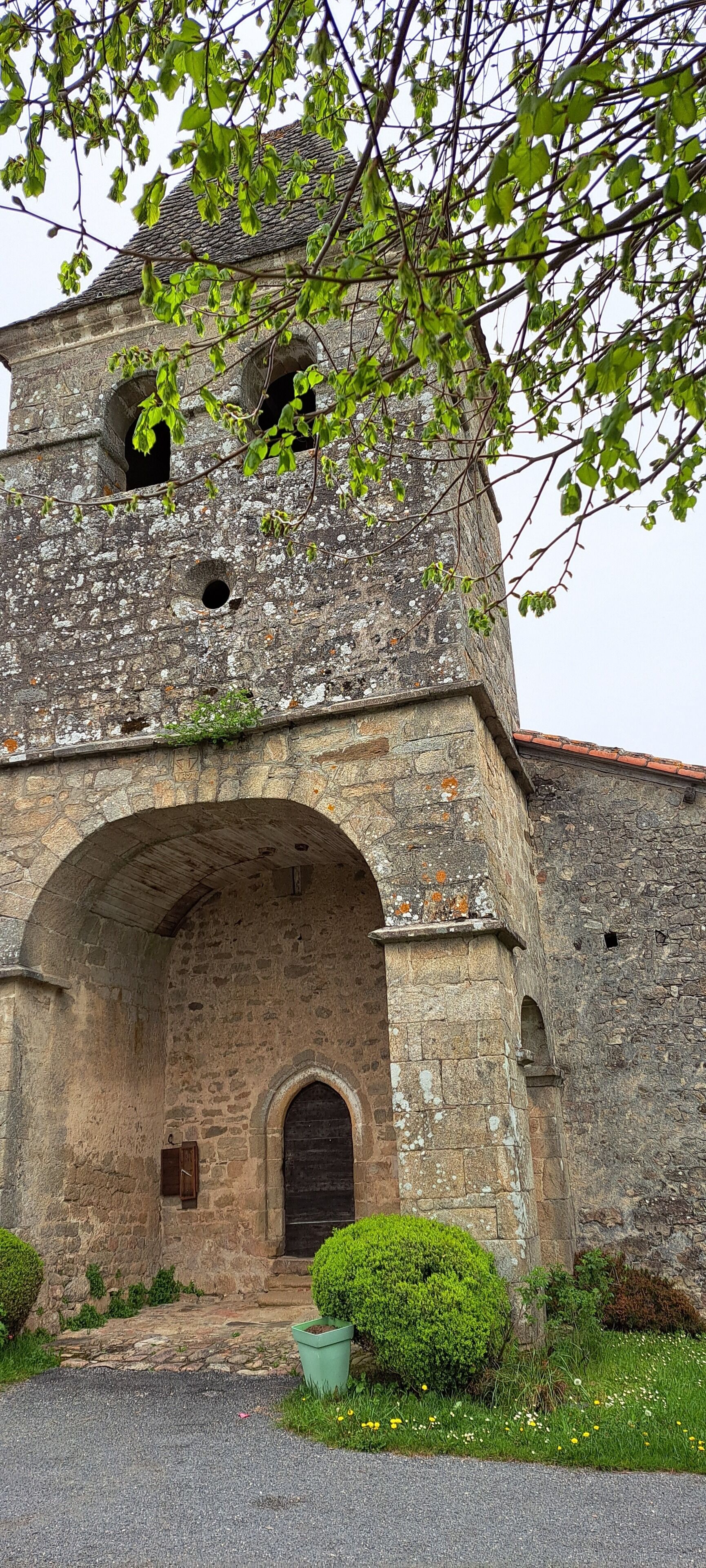 Un edificio de piedra con una entrada arqueada, una puerta pequeña y una ventana.