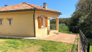 Un bâtiment jaune avec un toit en tuiles, un petit porche et une cour clôturée.