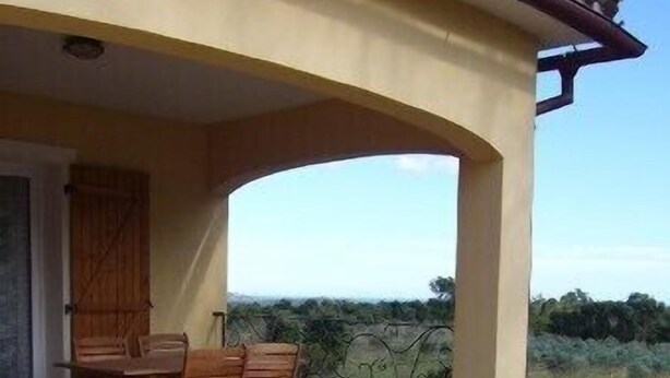 Une terrasse extérieure avec une table et des chaises, un espace abrité et une vue sur le paysage.