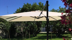 Una piscina con una tumbona blanca y un parasol grande que da sombra.