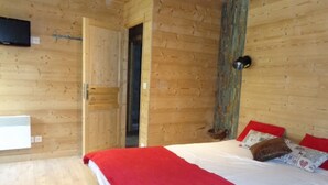 A wooden-paneled room with a bed, a red blanket, and a wall-mounted TV. - Chalet Haute Savoie quiet jacuzzi wifi near Lake Annecy (Thônes)