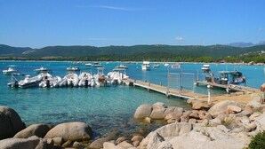 Un puerto deportivo con barcos amarrados, agua cristalina y terreno rocoso.