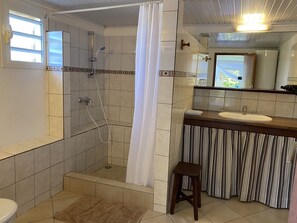 Chuveiro, secador de cabelo, toalhas de banho, papel higiênico