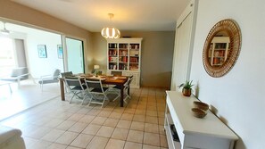 A dining area with a table and chairs, a bookshelf, and a decorative mirror.