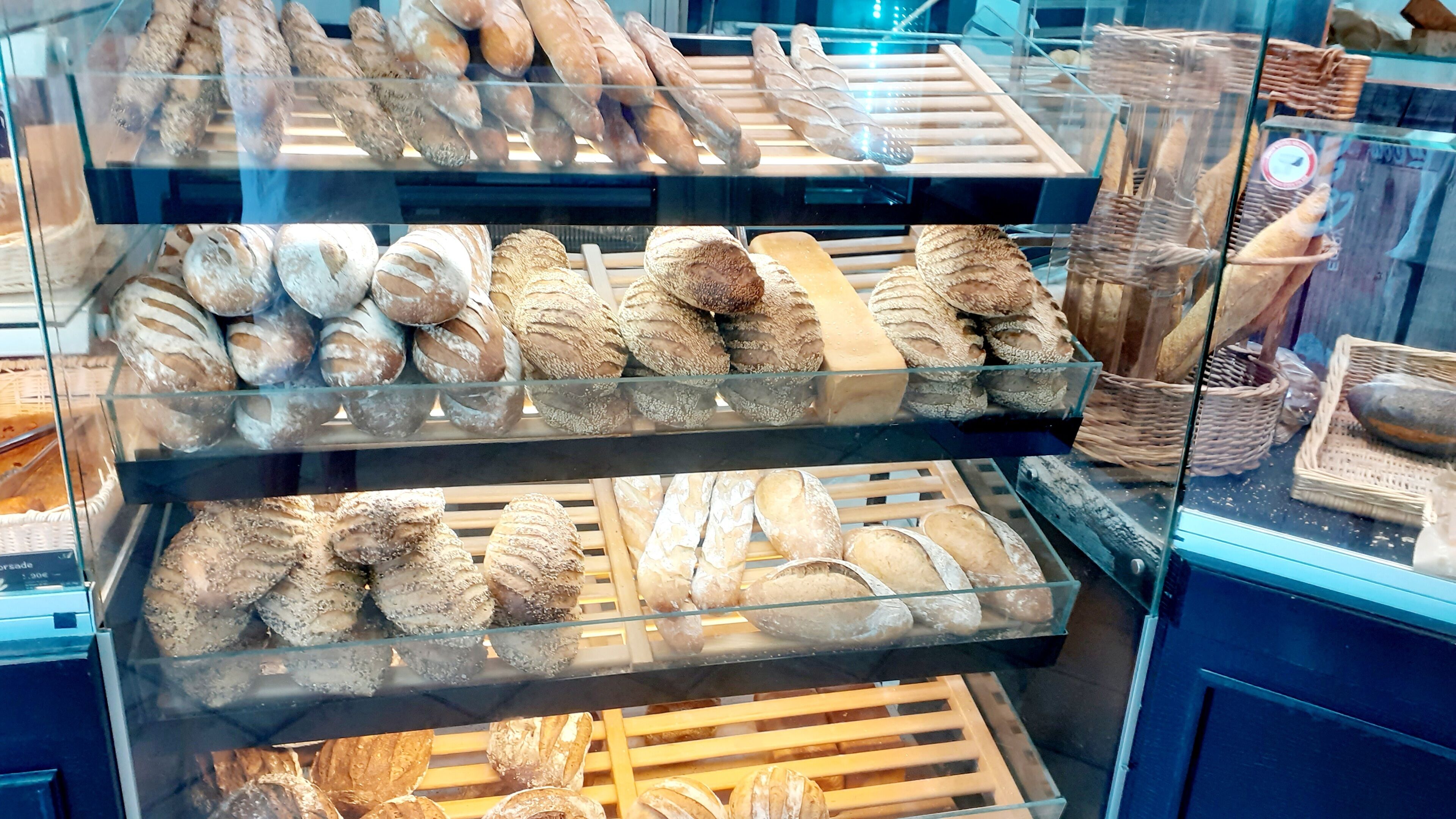 Une vitrine de boulangerie présentant différents types de pains et de pâtisseries.