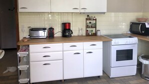 Una cocina con armarios blancos, un tostador, una cafetera, un microondas y una estufa.