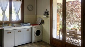 Cocina compacta con lavadora, lavaplatos y ventana con cortinas.