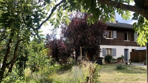 Un jardín con diversas plantas y una casa al fondo.
