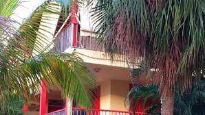 Un edificio de dos plantas con un balcón y barandilla roja.