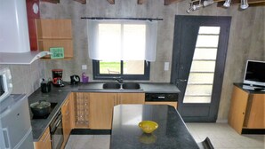 Uma cozinha moderna com ilha central, eletrodomésticos embutidos e uma grande janela que permite entrada de luz natural.