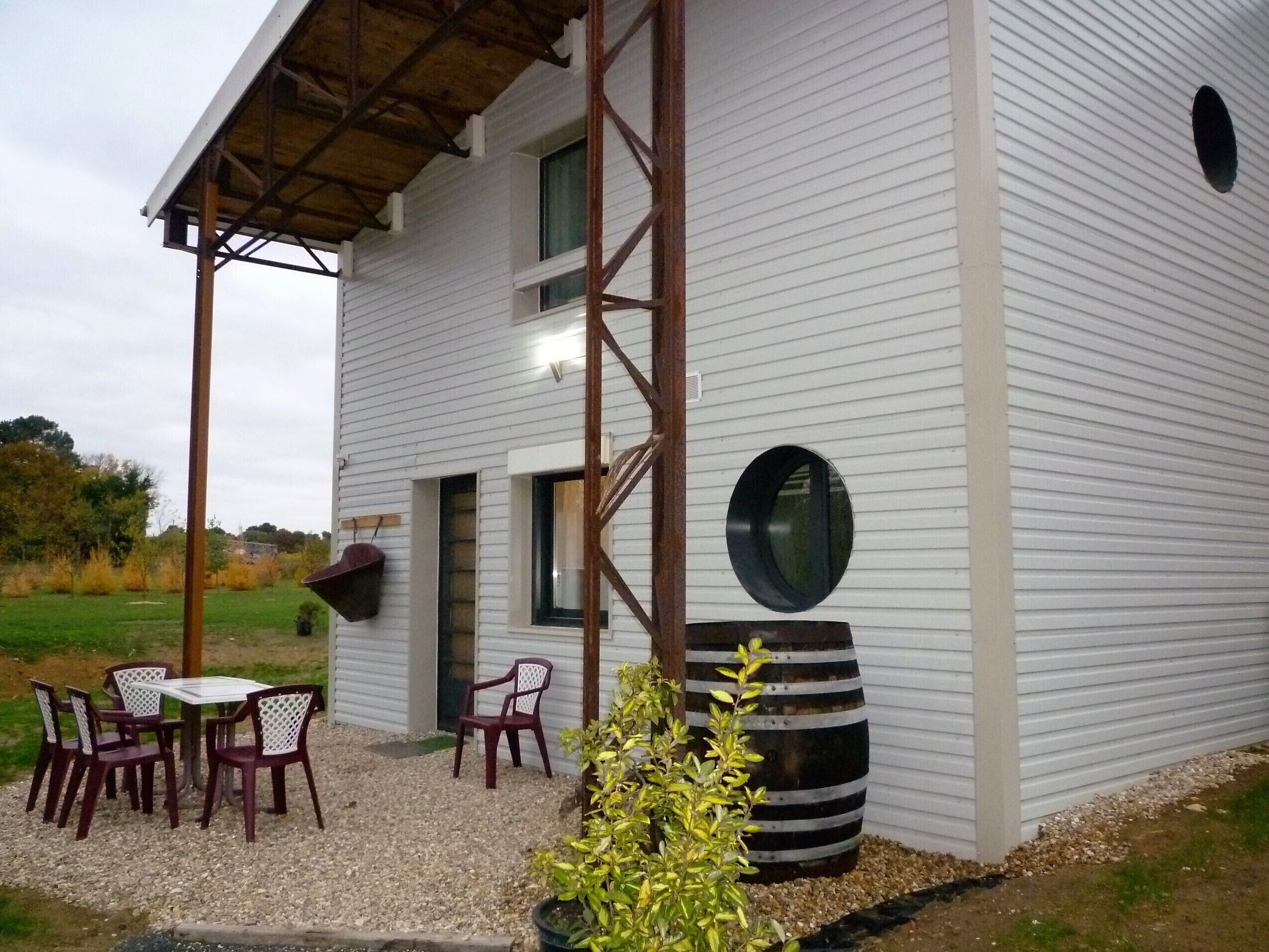 A modern house with a covered patio, a large round window, and a dining area with outdoor furniture.