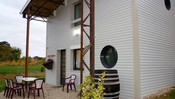 A modern house with a covered patio, a large round window, and a dining area with outdoor furniture.