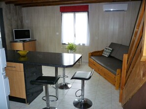 Una cocina compacta con comedor, un sofá y un televisor pequeño.