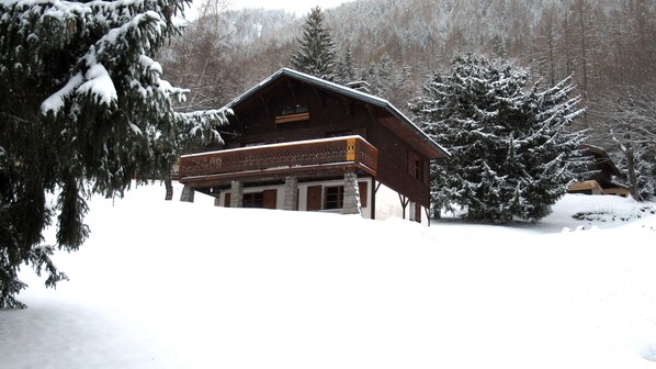 A wooden cabin with a balcony, surrounded by snow-covered trees.