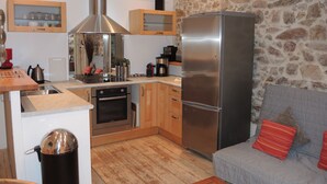 Eine moderne Küche mit Einbauofen, Edelstahlkühlschrank und Holzschränken.