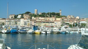Eine Marina mit vertäuten Booten, im Hintergrund eine historische Stadt und ein markanter Turm.