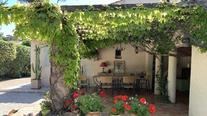 A patio with a table and chairs, surrounded by potted plants and a cactus. - Charming farmhouse in a 5000m2 field, private swimming pool, beach 200m away (Sainte-Maxime)