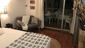 Een hotelkamer met een bed, een bank, een kleine tafel en een balkon met stoelen.