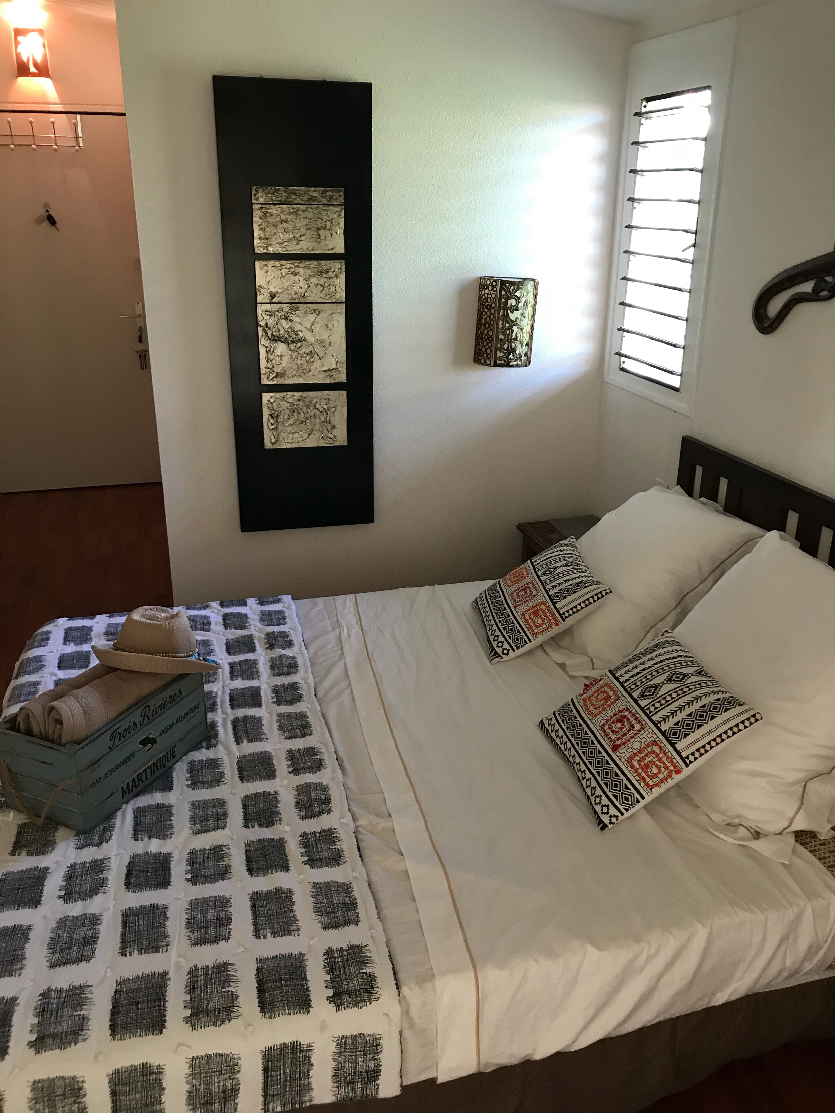 A neatly made bed with patterned pillows, a striped blanket, and a wooden headboard.