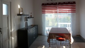 A dining area with a table, chairs, a chandelier, and a window with striped curtains.