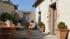 Une cour avec un mur en briques, une porte en bois et des plantes en pot.