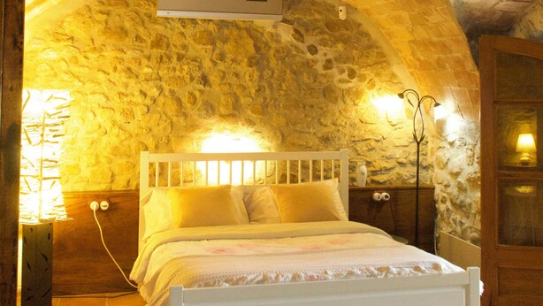 Ein Schlafzimmer mit einer Steingewölbe-Decke, einem weißen Bett und einem Nachttisch mit Lampe.