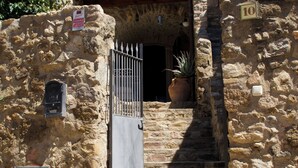 Eine Steintreppe führt zu einem Gebäudeeingang mit einem Metallgitter und einem Blumentopf.