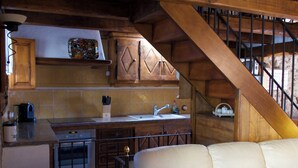 Eine kleine Küche mit Holzbalken, einem weißen Sofa und einer Treppe.