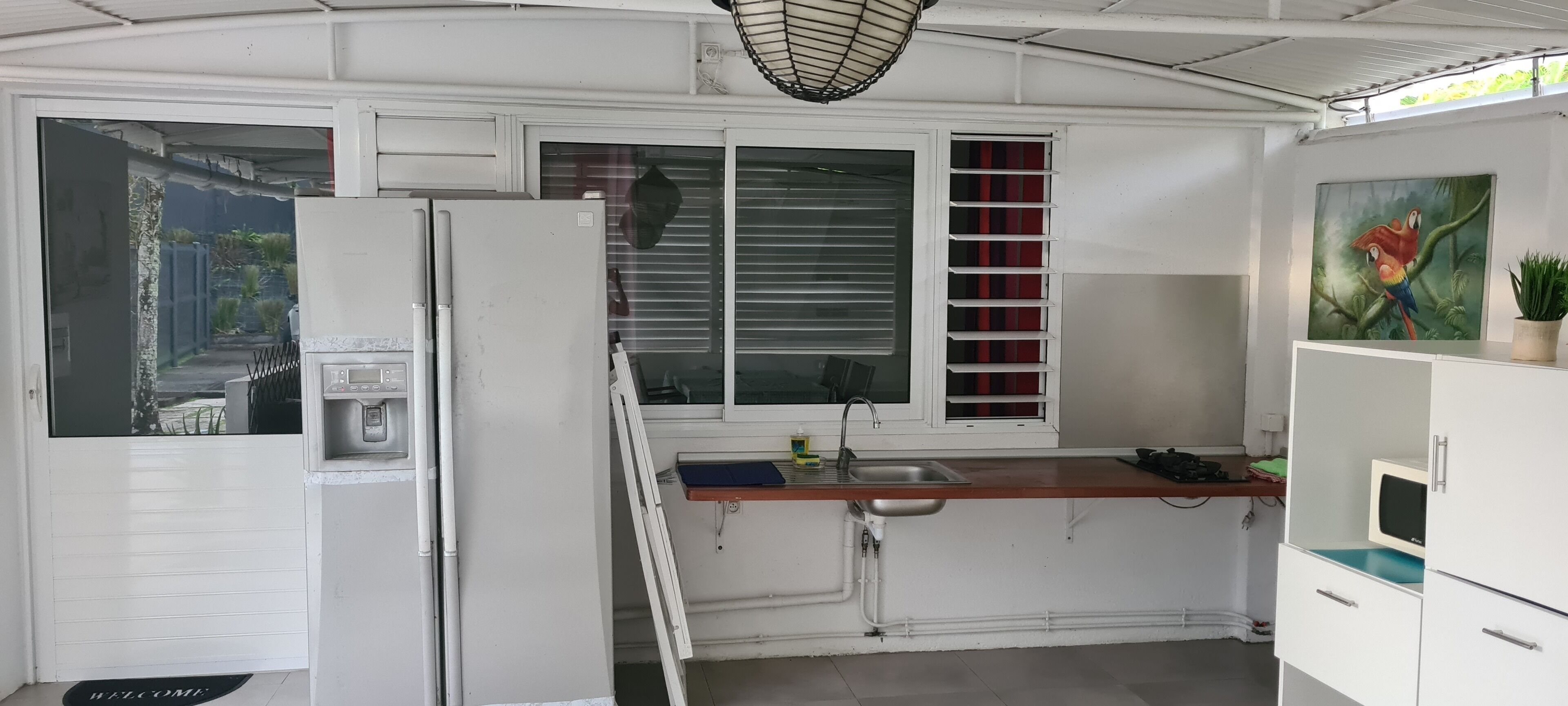 A compact kitchen with a built-in refrigerator, a sink, and a window with blinds.