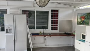 Een compacte keuken met een geïntegreerde koelkast, een spoelbak en een raam met zonwering.