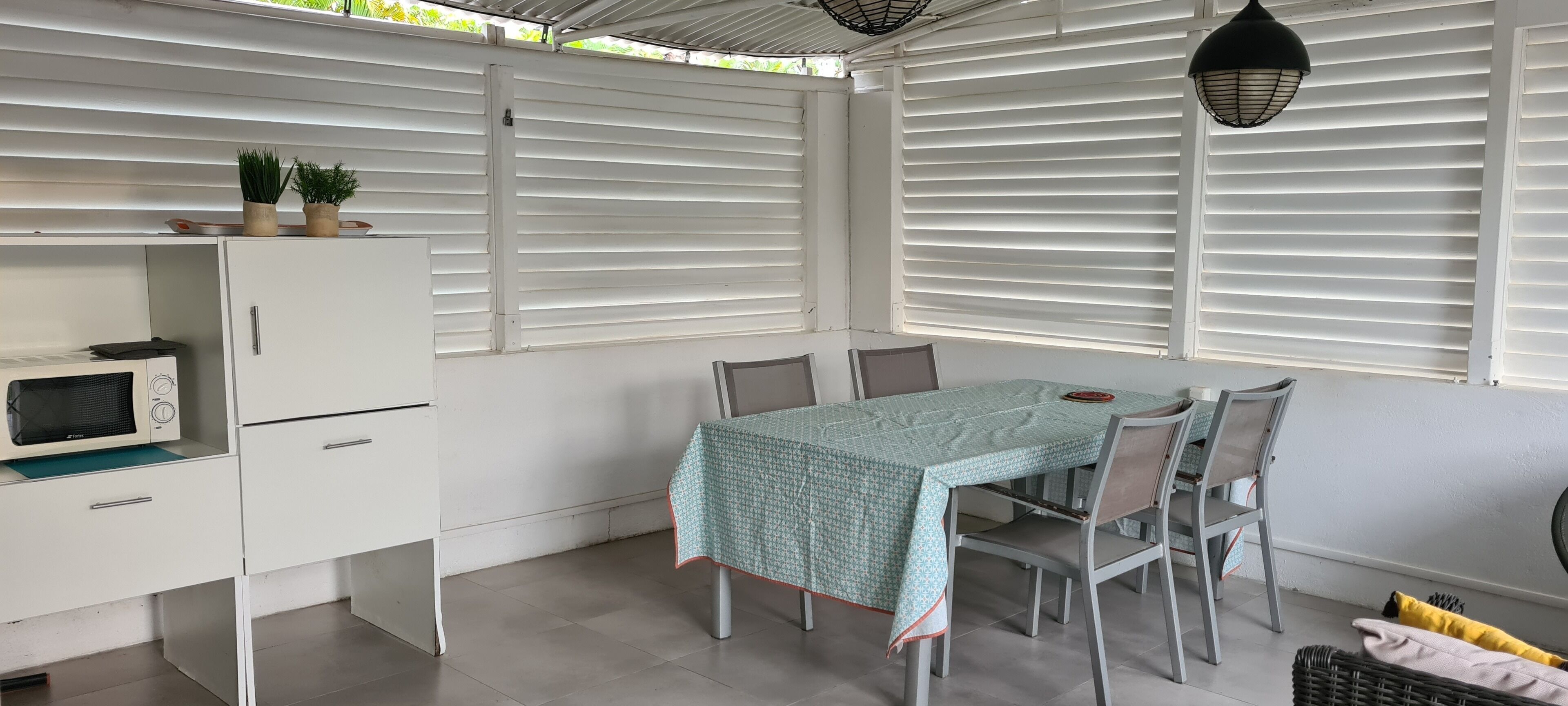 A compact kitchen with a microwave, a white cabinet, and a table with chairs.