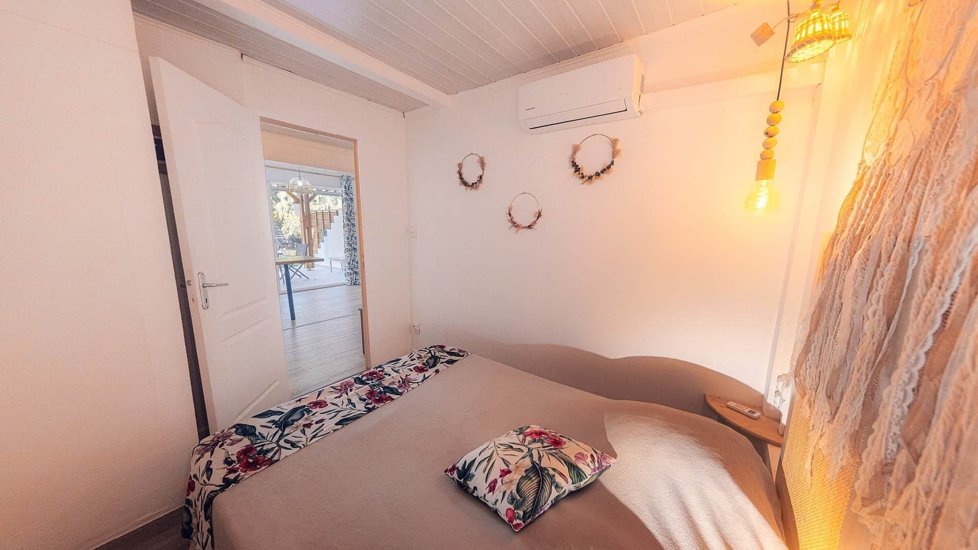 Ein Schlafzimmer mit einem Bett, einer Tür zu einem Außenbereich und einer Wand-Klimaanlage.